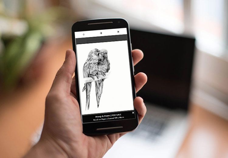 A hand holding a mobile phone displaying the Laura Pearse Wildlife Artist website.