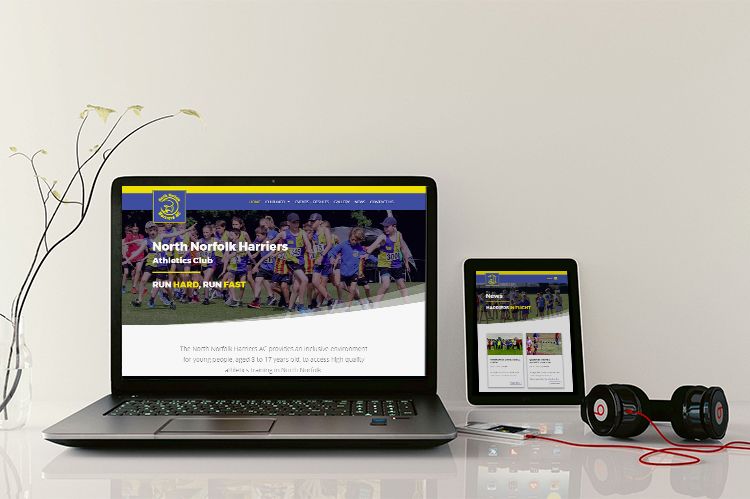 The North Norfolk Harriers website is displayed on a laptop and tablet device, sitting on top of a desk with a pair of black headphones.