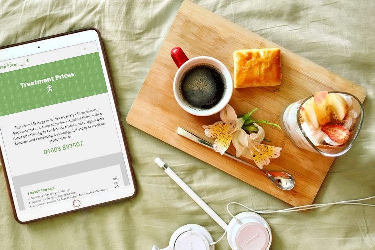The Top Form Massage website displayed on a tablet device, next to a healthy breakfast platter on a wooden tray.