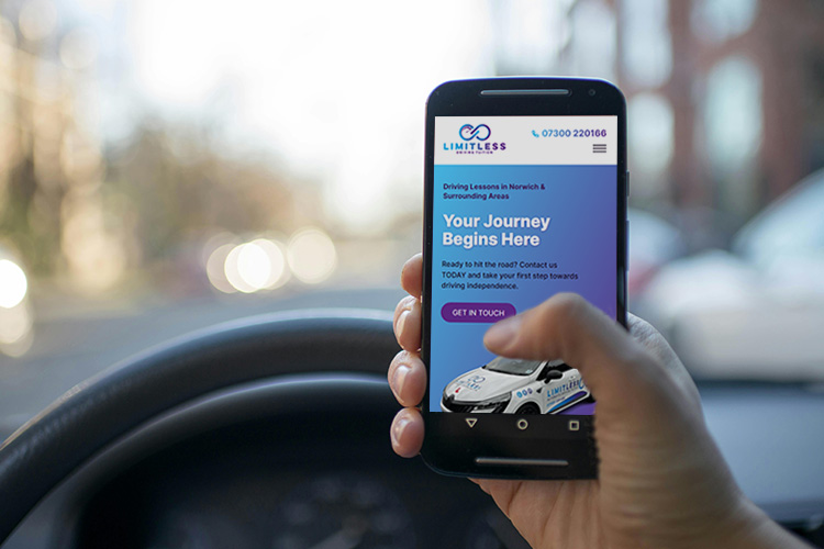 Person sitting in a car holding a mobile phone showing the Limitless Driving Tuition website