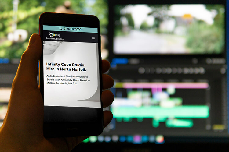 Creative Klousions website sidplayed on a mobile phone in a dark lit video production studio